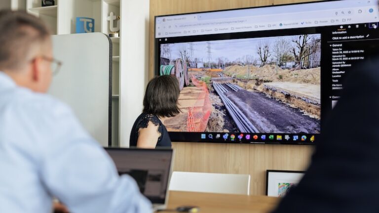 Office workers at a construction firm reviewing field work via a digital screen view