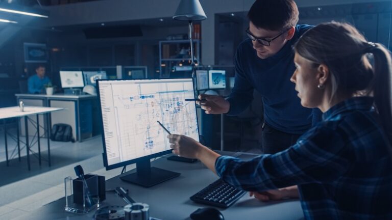 Two workers look at software integrations on desktop computer