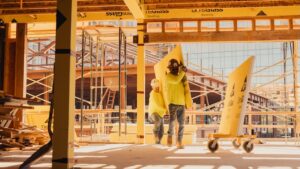 2 trade workers, one older and one younger, moving materials on a jobsite together